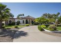 Captivating single-story home with stone accents, arched windows, and a circular driveway surrounded by mature trees at 12820 N 83Rd Pl, Scottsdale, AZ 85260
