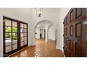 Wide foyer with red tile flooring, arched doorways, wood doors, and natural light at 13007 N 1St St, Phoenix, AZ 85022