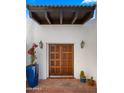 Close-up of front entrance featuring a double wooden door, potted plants, and a covered overhang at 13007 N 1St St, Phoenix, AZ 85022