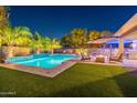 Beautiful backyard with a sparkling pool, palm trees, and a cozy fire pit area at 26879 N 100Th Ln, Peoria, AZ 85383