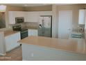 Well-lit kitchen with stainless steel refrigerator, white cabinets, and stylish countertops at 284 W Settlers Trl, Casa Grande, AZ 85122