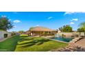 Expansive backyard featuring a sparkling pool, a covered patio, and a lush lawn at 6602 S Constellation Way, Gilbert, AZ 85298