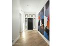 Bright entryway featuring hardwood floors, modern art, and a stylish black front door with sidelights at 7614 E Cactus Wren Rd, Scottsdale, AZ 85250
