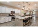 A modern kitchen features white cabinets, stainless appliances, and a large island with bar seating and granite countertops at 9834 E Thatcher Ave, Mesa, AZ 85212
