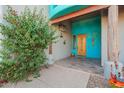 Inviting entryway showing a decorative wood door, unique turquoise paint and lush landscaping at 988 W Crooked Stick Dr, Casa Grande, AZ 85122