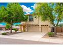 Tan two-story house features a two-car garage, desert landscaping, and mature shade trees at 1036 E Magnum Rd, San Tan Valley, AZ 85140
