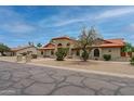 Charming single-story home boasting an arched entry, terra cotta roof, desert landscaping, and mature trees at 12899 W Pasadena Ave, Litchfield Park, AZ 85340