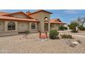 Close up of the home's front exterior showcasing the terra cotta roof, desert landscaping, and decorative bridge at 12899 W Pasadena Ave, Litchfield Park, AZ 85340