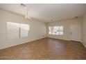 Bright living room features neutral walls, tile flooring, and ample natural light from large windows at 14552 W Hearn Rd, Surprise, AZ 85379
