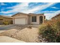 Single-story tan home featuring low maintenance desert landscaping and two car garage at 15134 N 138Th Ln, Surprise, AZ 85379