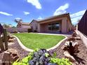 Lush backyard featuring a well-manicured artificial lawn, desert landscaping, and a covered patio with ample space at 3780 E Rakestraw Ln, Gilbert, AZ 85298