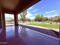 Covered patio with smooth flooring, a glimpse of a manicured backyard, desert landscaping, and secure fencing at 3780 E Rakestraw Ln, Gilbert, AZ 85298