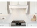 Close-up of a kitchen with white cabinets, white countertops, tile backsplash, and stainless steel appliances at 537 E Aurora Dr, San Tan Valley, AZ 85140