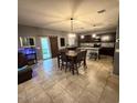 Open-concept living and dining area with tile floors, modern light fixture, and kitchen in background at 11644 W Redfield Rd, El Mirage, AZ 85335