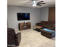 Comfortable living room features tile floors, a large TV, and brown sofas with coffee table at 11644 W Redfield Rd, El Mirage, AZ 85335