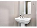 Elegant powder room features a pedestal sink and decorative textured walls at 11807 W Parkway Ln, Avondale, AZ 85323