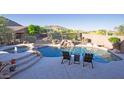 Backyard pool surrounded by rock accents, complemented by lounge chairs, natural vegetation, and a waterfall feature at 14045 E Geronimo Rd, Scottsdale, AZ 85259