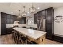 Modern kitchen featuring an island with marble countertops, stainless steel appliances, and dark wood cabinets at 1631 N Avoca --, Mesa, AZ 85207