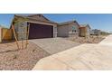 Attached garage features a dark brown door, stone driveway, desert landscaping, and taupe stucco at 25319 N 131St Dr, Peoria, AZ 85383