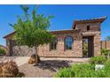 Close up of the front exterior with stone details, desert landscaping, arched windows, and gated entrance at 29703 N 70Th Ave, Peoria, AZ 85383