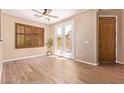 Bright living room featuring wood-look tile flooring, plantation shutters, and double French doors at 29703 N 70Th Ave, Peoria, AZ 85383