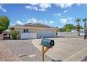 Charming single-story home featuring an expansive driveway with beautiful desert landscaping at 7001 E Flossmoor Ave, Mesa, AZ 85208