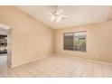 Bright living room with tile floors, a ceiling fan, and a large window overlooking the backyard at 12034 W Aster Dr, El Mirage, AZ 85335