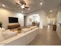 Open-concept living room with tile floors, neutral colors, ceiling fan, and an adjoining dining room at 1248 W Deoni Trl, San Tan Valley, AZ 85143