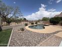 Beautiful backyard pool with desert landscaping, rock accents, and a secure metal fence at 1248 W Deoni Trl, San Tan Valley, AZ 85143