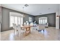 Elegant open-concept living and dining area with modern furniture, neutral tones, and tiled floors at 15731 W Redfield Rd, Surprise, AZ 85379