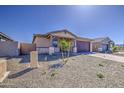 Single-story home with desert landscaping, brown stucco, brick driveway, and stone pillar accents at 17803 W Elm St, Goodyear, AZ 85395