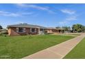 Quaint home boasts a lush green lawn, classic brick facade, and cozy front porch, perfect for relaxed outdoor living at 1944 W Osborn Rd, Phoenix, AZ 85015