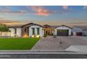 Charming single-story home featuring stone accents, lush lawn, manicured landscaping, and a two-car garage at 20165 E Via Del Palo Dr, Queen Creek, AZ 85142