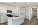 Well-lit kitchen with an island and stainless appliances, complemented by stylish wood-look flooring at 25283 N 183Rd Dr, Wittmann, AZ 85361