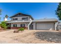 A two-story home with a wide driveway leading to an attached garage and mature trees on the property at 3201 W Evans Dr, Phoenix, AZ 85053