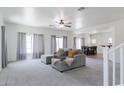 Spacious carpeted living room featuring a sectional couch and an open layout to the dining area at 44175 W Knauss Dr, Maricopa, AZ 85138