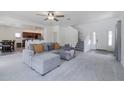 Open-concept living area flows into the dining room with gray sectional couch and staircase at 44175 W Knauss Dr, Maricopa, AZ 85138