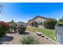 Lush backyard with a covered patio, beautiful flowers, and desert landscaping at 6742 W El Cortez Pl, Peoria, AZ 85383