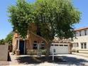 Charming two-story home featuring a well-manicured lawn, a two-car garage, and mature tree providing shade at 9132 S Parkside Dr, Tempe, AZ 85284