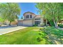Lovely home with a three-car garage, lush green lawn, and mature trees providing shade at 1361 E Sheffield Ave, Gilbert, AZ 85296