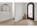 Bright foyer featuring tile flooring, a decorative mirror, and an arched doorway with a wrought iron gate at 1554 E Kings Ct, Gilbert, AZ 85234