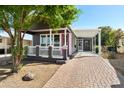 Inviting home exterior with a cozy porch, covered patio, and well-maintained brick driveway at 201 S Greenfield Rd # 215, Mesa, AZ 85206