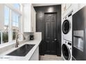 Modern laundry room features sleek countertops, a stacked washer/dryer, and contrasting black accents at 201 S Greenfield Rd # 215, Mesa, AZ 85206