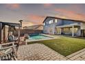 A luxurious backyard featuring a sparkling pool, cozy seating area, and a lush lawn at 13625 W Peck Ct, Litchfield Park, AZ 85340
