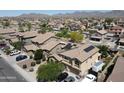 Expansive aerial view of a well-maintained community with mountain views and houses equipped with solar panels at 22022 W Moonlight Path, Buckeye, AZ 85326