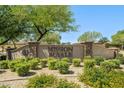 Community entrance with monument sign featuring landscaping, shrubbery and trees at 2592 E San Rafael Trl, Casa Grande, AZ 85194