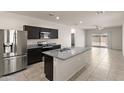 Modern kitchen with stainless steel appliances, granite countertops, and a center island overlooking the living area at 35266 W San Sisto Ave, Maricopa, AZ 85138