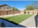 Spacious backyard featuring artificial turf, desert landscaping, and a concrete patio, perfect for outdoor living at 36114 W Vera Cruz Dr, Maricopa, AZ 85138