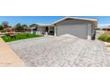 Well-maintained home featuring a brick-paved driveway and lush landscaping, offering great curb appeal at 5122 E Emerald Cir, Mesa, AZ 85206