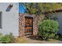 Rustic outdoor entrance with a wooden gate, a stone wall, and vibrant green foliage at 6418 E Sunnyside Dr, Scottsdale, AZ 85254